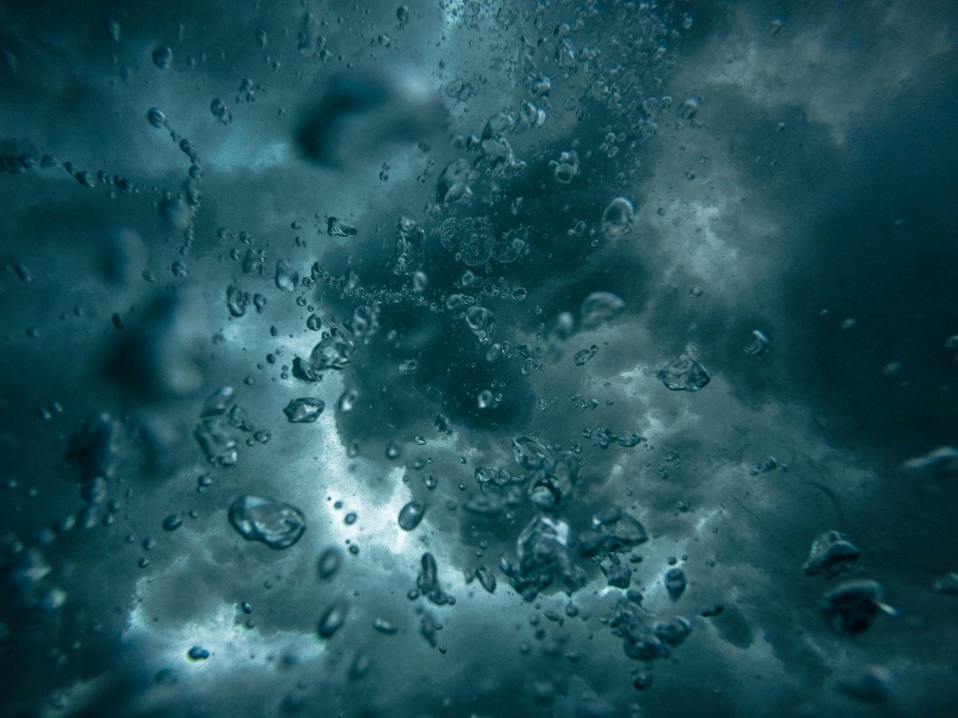 Beyond Preparedness - Raindrops falling against a window, looking up at a stormy grey sky, symbolising the challenges of climate change and the need for resilience.