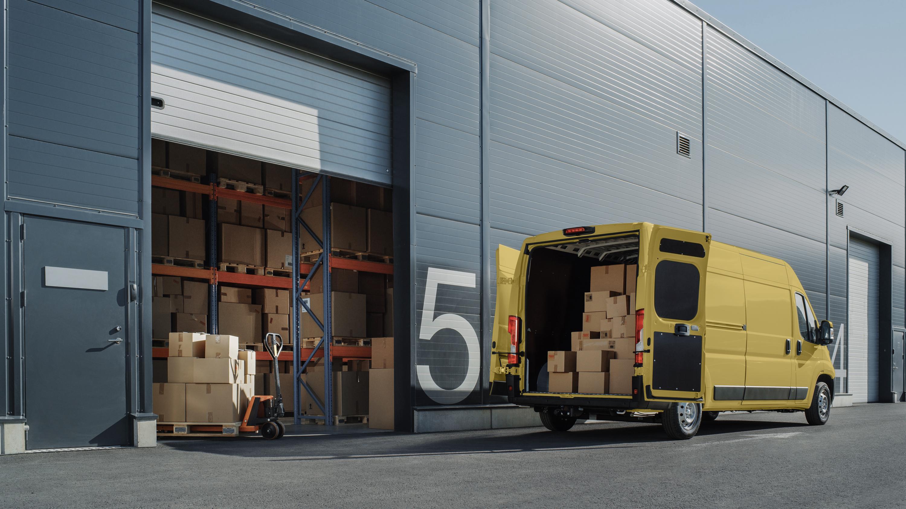 Yellow delivery van being loaded by a warehouse